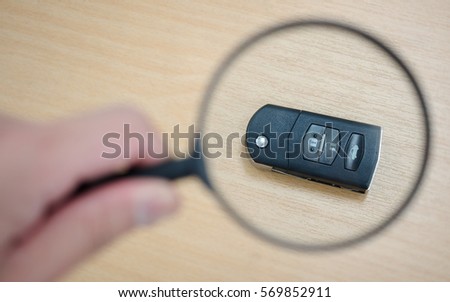 Searching a car key with magnifying glass. Concept of lost car key.