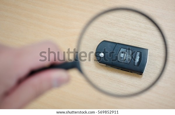 Searching a car key with magnifying glass. Concept\
of lost car key.