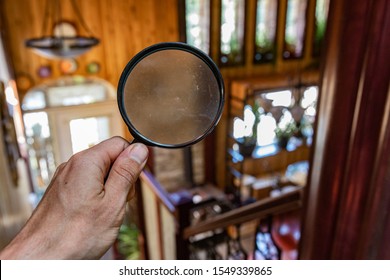 Searching Inside A Family Home, Looking Through The Lens Of A Magnifying Glass In First Person Perspective With Blurry Background And Copy Space.