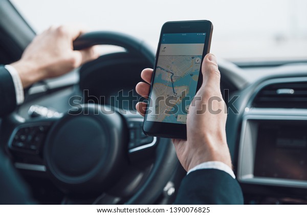 Searching for the\
shortest way. Close up of young man using smart phone to check the\
map while driving a car \
