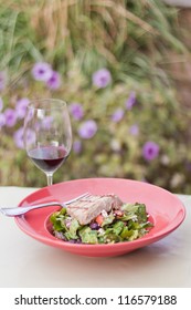 Seared Ahi Tuna Salad Served Outdoors With A Glass Of Wine