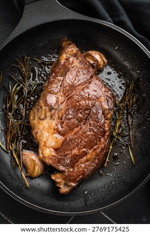 Seared beef chuck eye roll steak in skillet with rosemary and butter. Gourmet beef dish with rich flavor and copy space