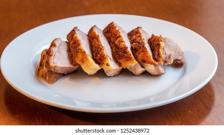 Seared duck breast with crispy skin on a white ceramic plate 