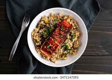 Seared Salmon with Mushroom Risotto in a Pasta Bowl: Marinated salmon fish fillet on a bed of mushroom risotto with scallions and sesame seed garnish - Powered by Shutterstock