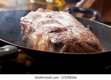 Searing Of An Organic Grass Fed Cross Rib Roast With Steam Coming Off Of It And A Bottle Of Olive Oil In The Background