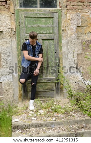 Searious guy is stangding at thi old green door.