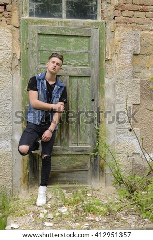 Searious guy is stangding at thi old green door.