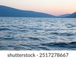 Seascape with blue silhouettes of the mountains after sunset for publication, design, poster, calendar, post, screensaver, wallpaper, postcard, banner, cover, website. High quality photography