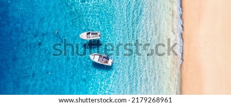 Seascape with boats near beach. Aerial view of floating boat on blue sea at sunny day. Top view from drone at beach and blue sea. Vacation and holidays