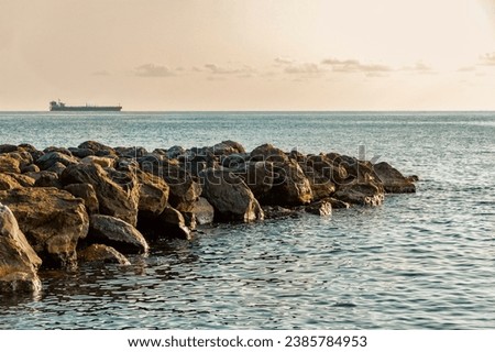 Seascape. A breakwater made of stones. A beach with a breakwater made of large stone boulders. View of the sea breakwater made of stones. A dam near the seashore in summer. Stock fotó © 