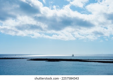 Seascape and cloudscape in blue color. Calm sea on a sunny day with clouds horizontal landscape background.  Distant boat silhouette in the ocean. - Shutterstock ID 2257584343