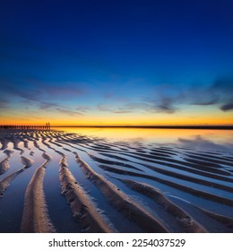 A seascape during sunset. Lines of sand on the seashore. Bright sky during sunset. A sandy beach at low tide. Travel image. Photography for design. - Shutterstock ID 2254037529