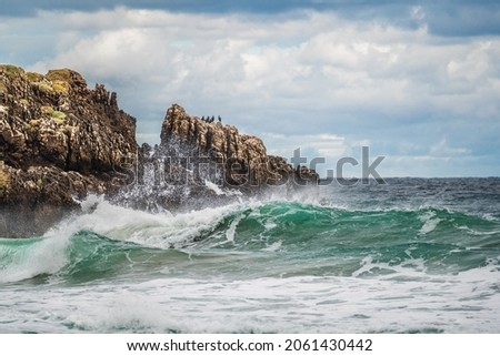 seascape with gloomy sky, sharp rocks and big waves on the sea. Powerful waves on ocean. Rugged cliffs and swirling sea. Rugged, rocky coastline with water swirling around rocks