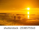 Seascape on Andoya island with people walking on beach at midnight sun, Vesteralen archipelago, Norway.