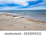 Seascape on coastal beach, boat overturned on sand, others in waters of Sea of Cortez, peninsula and horizon against blue sky with white clouds in background, La Paz, Baja California Sur Mexico