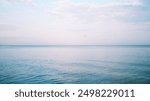 Seascape. Purple minimalist landscape. Calm sea. Horizon. Clear horizon. Clouds in the sky. Sunset. Pink colors