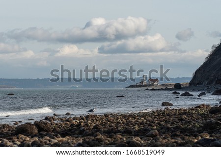 Seascape of rocky shoreline, pacific ocean and distant lighthouse at Fort Worden State Park in Port Townsend, Washington Stockfoto © 
