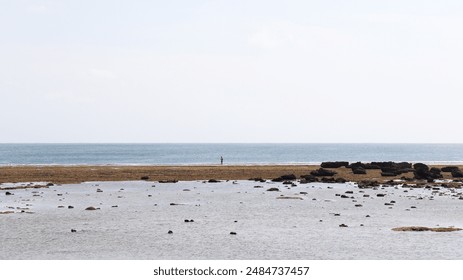 Seascape with a Solitary Figure Standing on a Rocky Shoreline. - Powered by Shutterstock