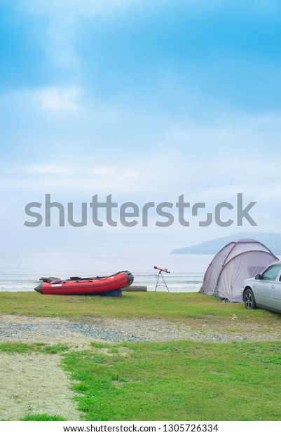 Seascape summer travel machine tent rubber boat.\
Coastline horizon sky with\
clouds