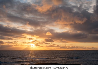 Seascape Sunset, Dark Ocean, With Sun Hidden By Yellow Clouds, Mix Of Other Colors. Bright Yellow Sun Rays Reaching The Ocean, Yellow, Orange, Grey, And White Clouds. 