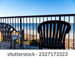 Seascape view through balcony railing with two chairs at Myrtle Beach resort hotel condo condominium apartment waterfront building, South Carolina