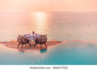 Seascape view under sunset light with dining table with infinity pool around. Romantic tropical getaway for two, couple concept. Chairs, food and romance. Luxury destination dining, honeymoon template - Shutterstock ID 2064277223