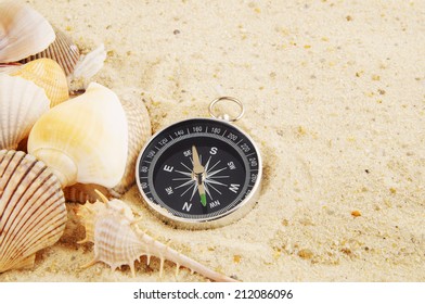 Seashells with compass on sand background, travel concept - Shutterstock ID 212086096