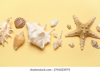 Seashells and starfish flat lay border on pastel yellow background with copy space, summer beach vacation marine decor and coastal nature arrangement