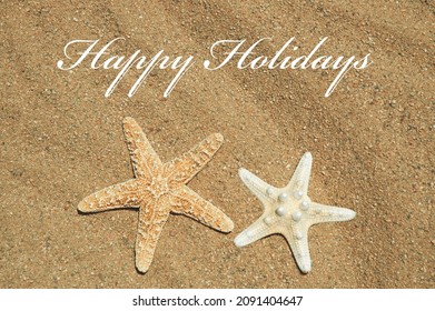 Seaside holiday greeting concept. Two starfish on the beach with the greeting Happy Holidays. - Powered by Shutterstock