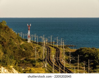 Seaside Railway Landscape: An Electrified Double-track Railway On The Seashore And A Cell Tower On A Sunny Summer Day