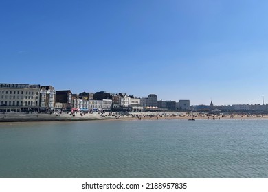 Seaside Town Of Margate, Kent, England, UK. People Sun Bathing On The Sea Front Beautiful Spring Day. Clear Water And Blue Skies.