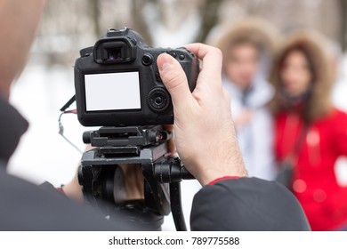 season, hobby, art work concept. close up of professional camera with blank screen in the arm of photographer on the background of two models that wear winter clothes - Shutterstock ID 789775588