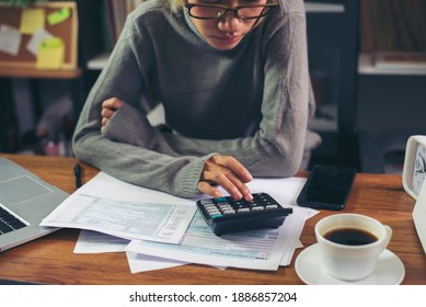 Season To Pay Tax And Budget Planning Concept. Business Woman Calculating Annual Tax And Using Mobile Phone. Calendar 2021 And Personal Income Tax Form Placed On Home Office Desk.