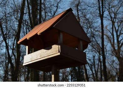 Seasonal bird feeder with made of right roof tiles made of burnt clay. Forest park seed, winter. Fungus shape made of carved wood. Children like such a house - Shutterstock ID 2255129351