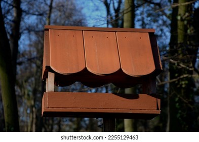 Seasonal bird feeder with made of right roof tiles made of burnt clay. Forest park seed, winter. Fungus shape made of carved wood. Children like such a house - Shutterstock ID 2255129463