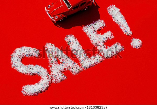 Seasonal car sales, Black Friday,\
new year discounts and shopping concept. A sale sign and a red car\
on a red background. Flat lay.Russia, Moscow, January,\
2020