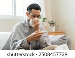 Seasonal cold sickness in people concept, Sick asian man looking at thermometer during measuring his body temperature feel exhausted and headache from fever.