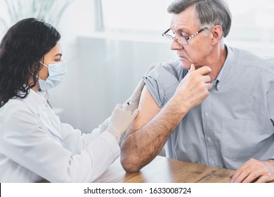 Seasonal Flu Shot. Brazilian Nurse In Medical Mask Injecting Tetanus Toxoid Vaccine To Senior Retired Man, Copyspace