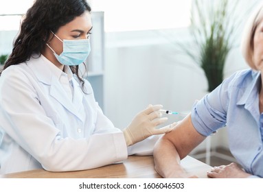 Seasonal Flu Shot. Mexican Doctor In Medical Mask Injecting Tetanus Toxoid Vaccine To Mature Woman, Copy Space