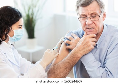 Seasonal Flu Shot. Mexican Doctor In Medical Mask Injecting Tetanus Toxoid Vaccine To Mature Man, Copy Space