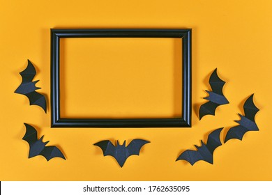 Seasonal Halloween Flat Lay With Black Flying Paper Craft Bats Around Empty Picture Frame On Orange Background