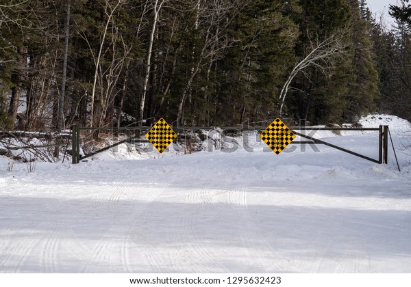 A seasonal road closure\
gate in Banff National Park Canada along the Bow Valley Parkway\
prevents tourists from venturing on a dangerous snow covered,\
unmaintained road