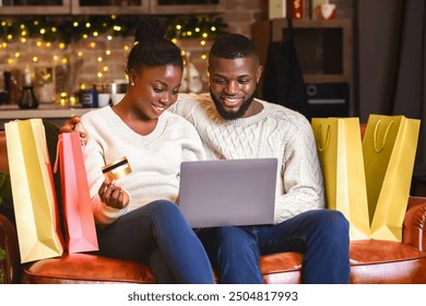 Seasonal sales. Happy african american couple buying Christmas presents online, using laptop and credit card. - Powered by Shutterstock