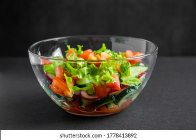 Seasonal summer vegetable salad in a glass bowl on a dark background. Vegan organic food, dietary meal in a rustic style. - Powered by Shutterstock