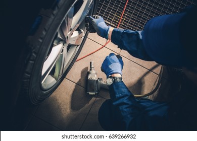 Seasonal Tire Replacement. Car Service Worker Replacing Vehicle Tires And Rotate The Wheels.