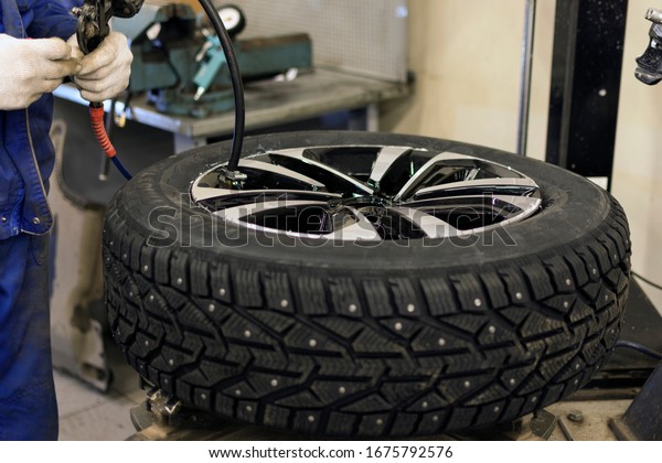 Seasonal winter tire service. Professional mechanic\
in a car service. A car wheel on a machine for replacing tires. A\
mechanic at work.