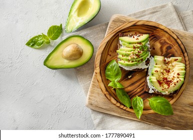 Seasoned avocado sandwiches in wooden plate on white background. Top view.