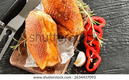 Seasoned pieces of grilled meat placed on a kitchen table surrounded by fresh ingredients, vegetables and herbs. Healthy eating, home cooking, food blogs and conscious food preparation concept.