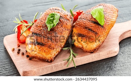 Seasoned pieces of grilled meat placed on a kitchen table surrounded by fresh ingredients, vegetables and herbs. Healthy eating, home cooking, food blogs and conscious food preparation concept.