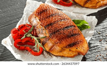 Seasoned pieces of grilled meat placed on a kitchen table surrounded by fresh ingredients, vegetables and herbs. Healthy eating, home cooking, food blogs and conscious food preparation concept.